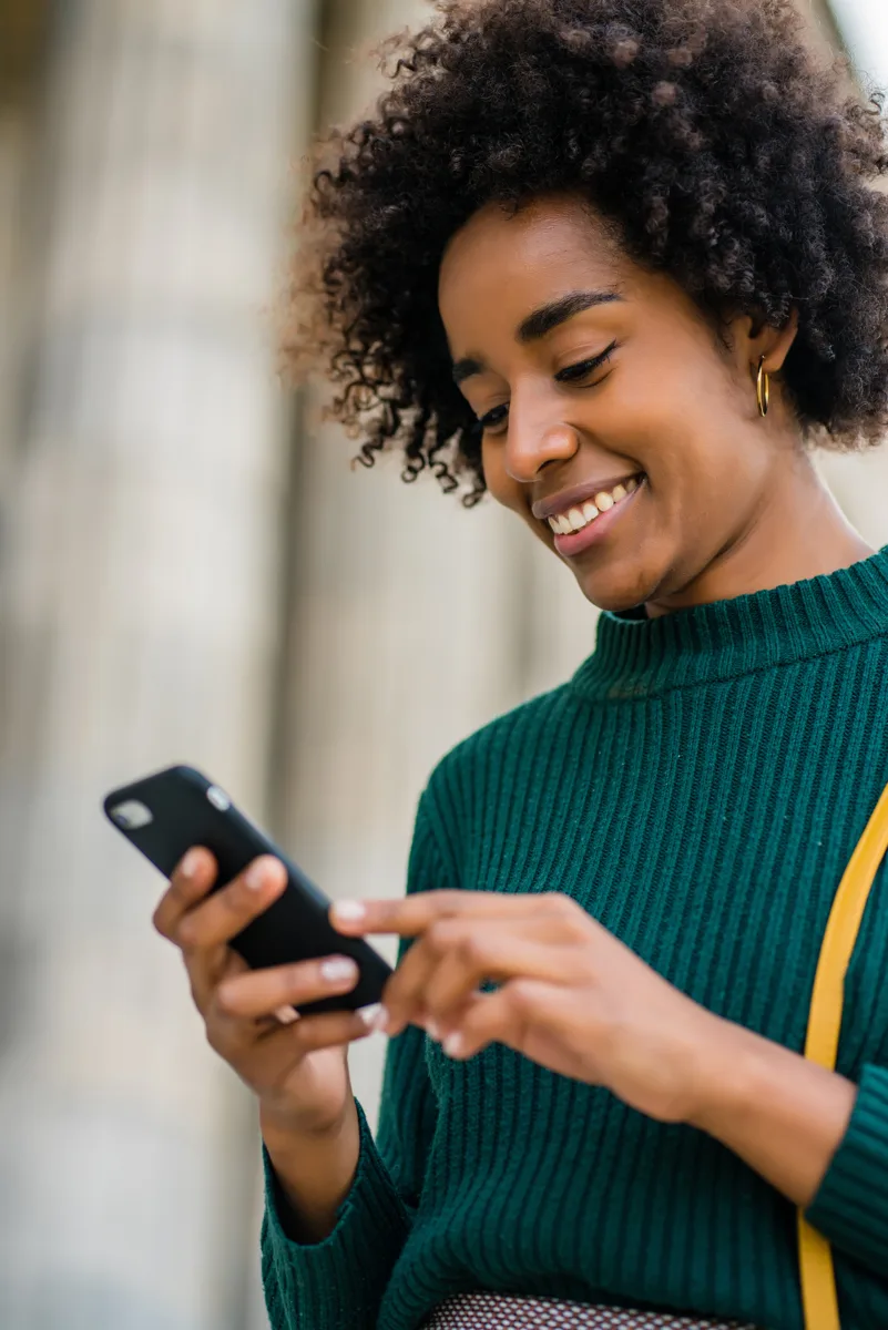 Mulher sorrindo enquanto usa o celular